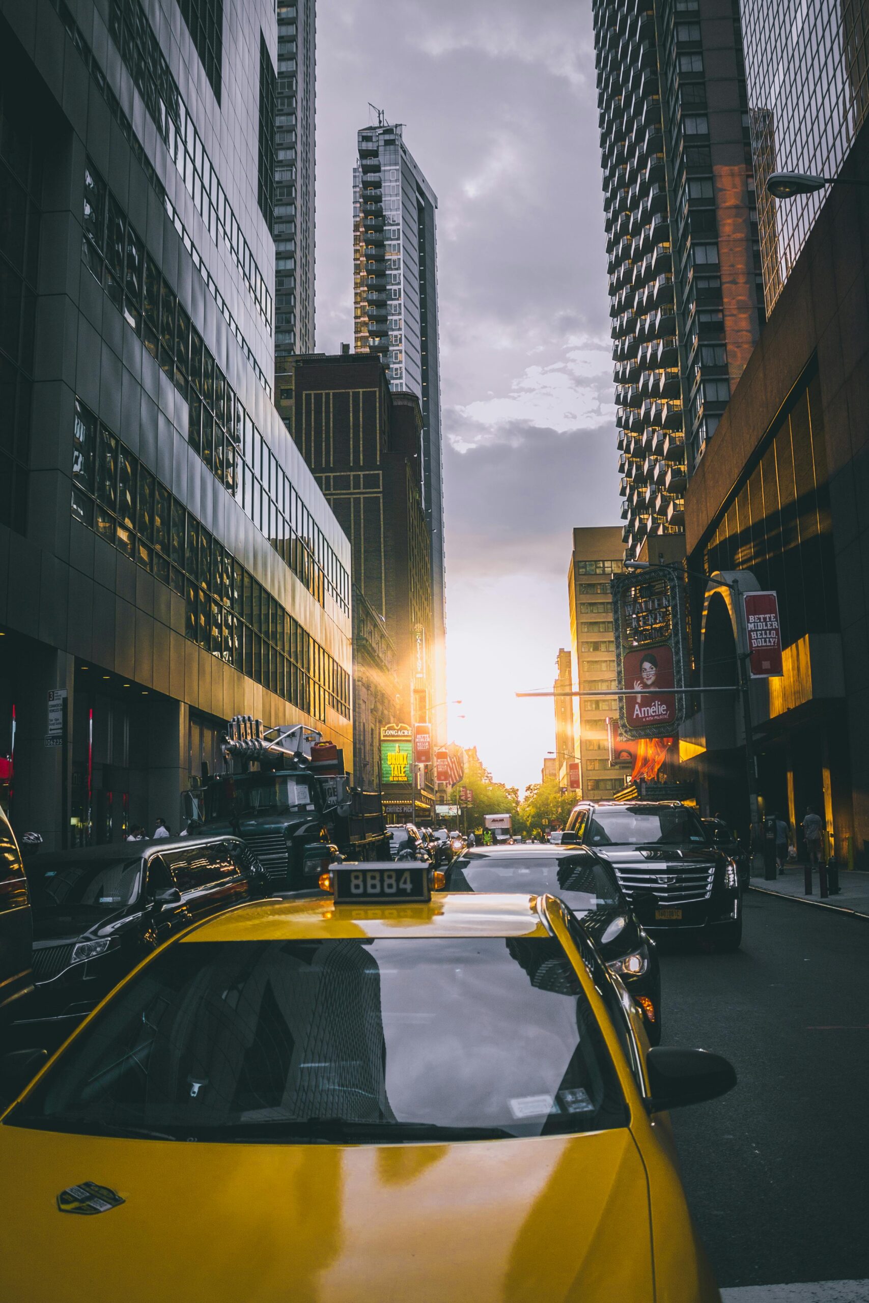 Yellow taxi amidst busy New York City traffic with skyscrapers at sunset.